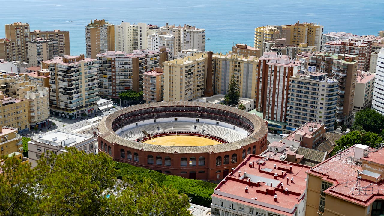 service-01 Aerial view of La Malagueta bullring surrounded by Málaga's urban landscape and coastline.