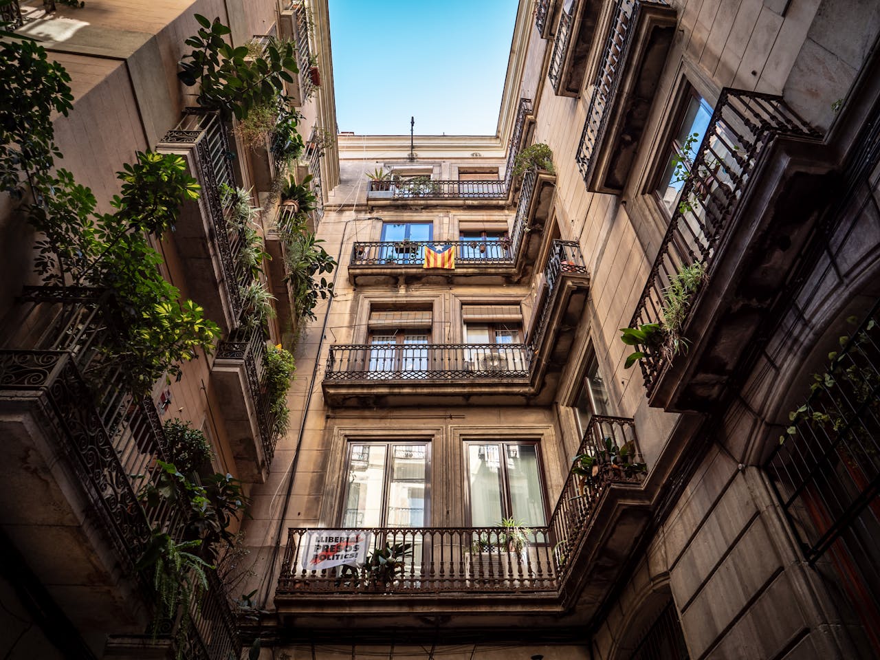 Low angle shot of a historic Barcelona building with balconies adorned with plants.