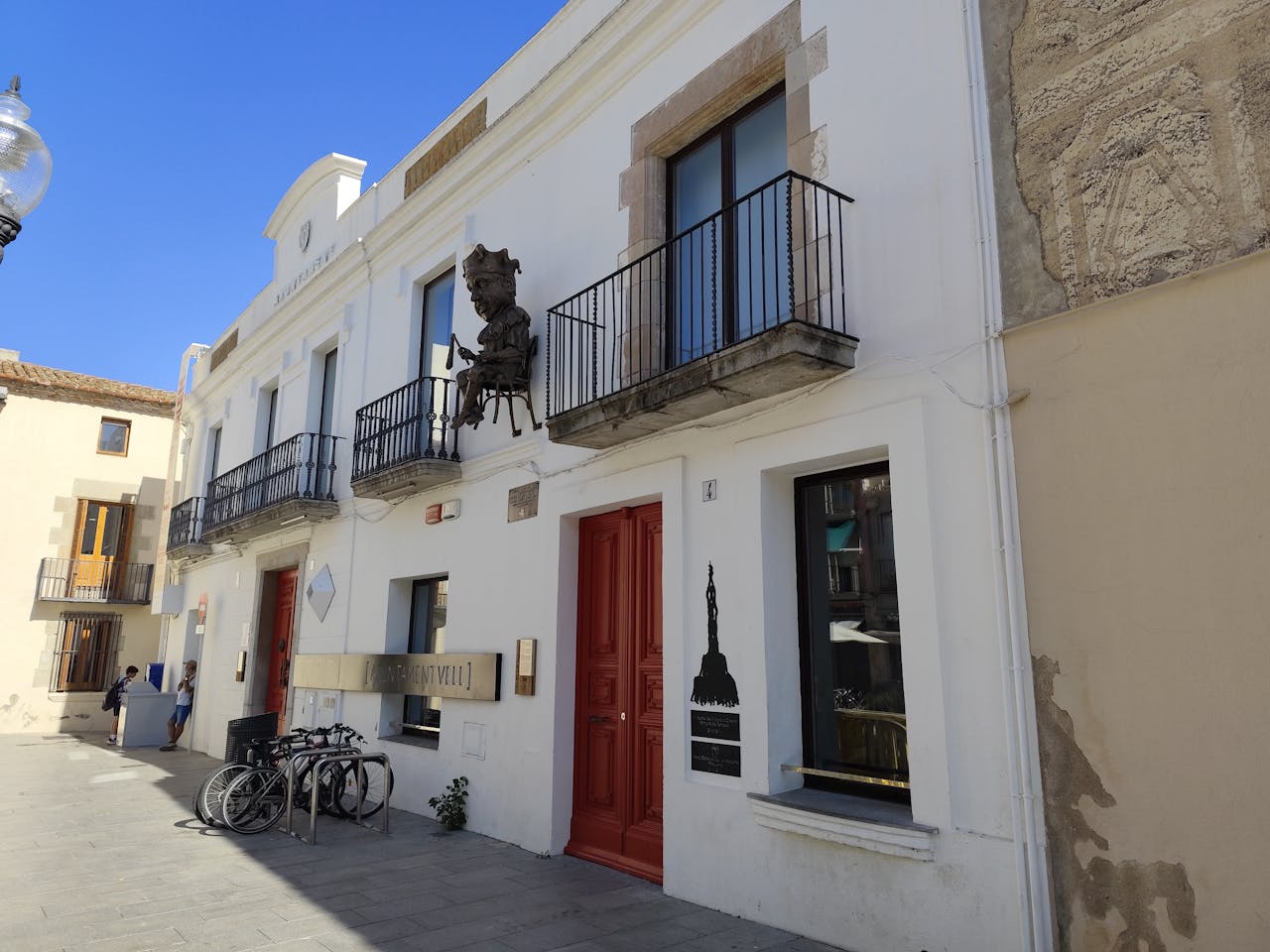 hero-img Charming street in Calella featuring historic architecture and outdoor bicycles.